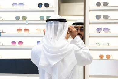فحص النظارات قبل الشراء، متعة التسويق والشراء ، التسوق فى احدي المولات الاماراتيه ، صورة مقربة لرجل عربي خليجي اماراتي يرتدي الكندره يقوم باختيار نظاره طبيه
