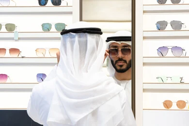 The joy of shopping and buying, checking glasses before buying, a close-up of an Emirati Gulf Arab man wearing a kandara choosing glasses, the confusion of choosing