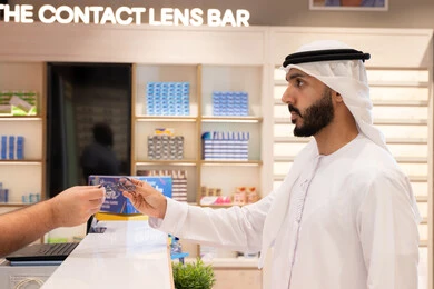 شاب عربي خليجي اماراتي يرتدي الكندوره والغتره البيضاء يقوم بشراء النظارة الطبيه المناسبة في محل نظارات ,الاهتمام بالمظهر الخارجي، شراء النظارات الخاصة بضعف النظر، تحسين الرؤية ومحاولة تعديل البصر، التسوق وشراء النظارات الطبيه