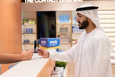 الاهتمام بالمظهر الخارجي، شراء النظارات الخاصة بضعف النظر، تحسين الرؤية ومحاولة تعديل البصر، شاب عربي خليجي اماراتي يرتدي الكندوره والغتره البيضاء يقوم بشراء النظارة الطبيه المناسبة في محل نظارات , التسوق وشراء النظارات الطبيه