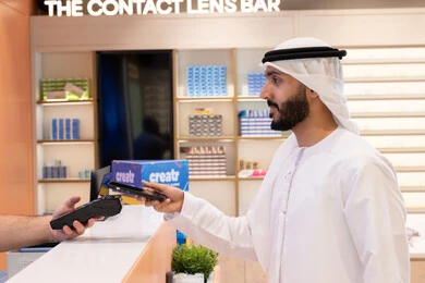 An Emirati Gulf Arab man makes an electronic payment, purchasing gifts from an Emirati mall, using online shopping and purchasing applications via phone, completing the payment process using a mobile phone.