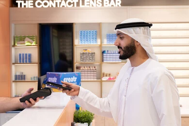 اقتناء وشراء هدايا من احدي المولات الاماراتيه، تطبيقات التسوق والشراء الالكتروني عبر الهاتف، إتمام عملية الدفع باستخدام الهاتف المحمول، رجل عربي خليجي اماراتي يقوم بالدفع الالكتروني