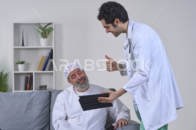 رفع اصبع الابهام للاعلى بإيماءات الاعجاب، متابعة السجل الطبي الالكتروني, ممرض يرتدي المعطف يقوم بوصف الحالة المرضية باستخدام جهاز التابليت، تقديم أفضل الخدمات الطبية المنزلية، بورتريه لرجل كبير السن عربي خليجي اماراتي يرتدي الكندورة ويجلس على الكنبه، خلفية بيضاء