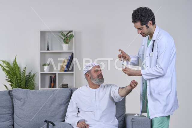 الاستعداد لأخذ الحقنة المسكنة للألم، مفهوم العمل في شركات التمريض المنزلي، تقديم أفضل الخدمات الطبية المنزلية للمرضى كبار السن، بورتريه لممرض يرتدي اللباس الطبي يقوم بإعطاء ابرة لرجل كبير بالسن عربي خليجي اماراتي يرتدي الكندورة ويجلس على كنبه، خلفية بيضاء