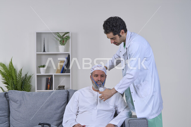 المحافظة على ممر هوائي منتظم باستخدام جهاز التنفس الصناعي، تقديم الرعاية الصحية المنزلية، بورتريه لممرض يرتدي المعطف الطبي يقوم بوضع قناع الأكسجين لمريض عربي خليجي اماراتي، استنشاق أدوية معالجة لانقطاع التنفس، مداواة أمراض الربو المزمنة، خلفية بيضاء