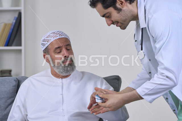 Attention and regular follow-up of home checkups, doctor wearing coat holding digital infrared pulse oximeter, close-up portrait of nurse checking blood oxygen level of elderly Arab Gulf Emirati patient wearing kandura and hat, working in medical sector, white background
