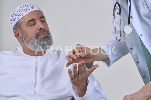 الاهتمام بالصحة والالتزام بالأوقات الصحيحة لأخذ العلاج, استخدام عقار الدواء بوصفة طبية, العمل في القطاع الطبي وشركات التمريض المنزلي، بورتريه مقرب لممرض يرتدي المعطف الطبي يقوم بإعطاء حبوب الدواء لمريض مسن عربي خليجي اماراتي يرتدي الكندورة، خلفية بيضاء