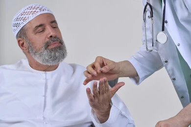 الاهتمام بالصحة والالتزام بالأوقات الصحيحة لأخذ العلاج, استخدام عقار الدواء بوصفة طبية, العمل في القطاع الطبي وشركات التمريض المنزلي، بورتريه مقرب لممرض يرتدي المعطف الطبي يقوم بإعطاء حبوب الدواء لمريض مسن عربي خليجي اماراتي يرتدي الكندورة، خلفية بيضاء