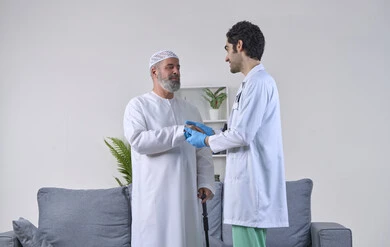 Home nursing companies, thanking and appreciating the doctor for his efforts and medical care, providing the best medical services to elderly patients, working in the health field, portrait of an elderly Emirati Gulf Arab man wearing a kandura and hat and shaking hands with the nurse with gestures of gratitude, full body image, white background