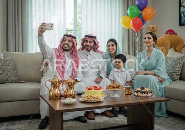 Taking family photos using a mobile phone, Islamic religious holidays and occasions, the Eid atmosphere in Saudi Arabian society, family gatherings and visits during Eid al-Adha, good hospitality and reception of guests, the concept of kinship and family bonding.