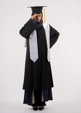 التعب والارهاق بعد الاجتهاد والمثابرة، بورتريه لشابة عربية خليجية اماراتية ترتدي القبعة وزي التخرج تضع يدها على رأسها بتعابير اليأس، الانتهاء من مرحلة الدراسة الجامعية بعد عناء، خريجة اماراتية تنتظر نتائجها، الجسم بالطول الكامل، خلفية بيضاء