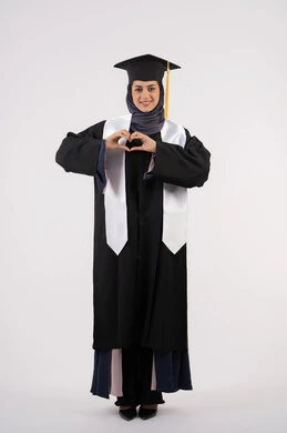 تشكيل اليد على شكل قلب،خريجة اماراتية تحتفل بإنهاء المرحلة الجامعية، بورتريه لشابة عربية خليجية سعودية مبتسمة ترتدي القبعة وعباءة التخرج تنظر الى الكاميرا بتعابير السرور والسعادة، مفهوم التفوق والنجاح والاجتهاد، الجسم بالطول الكامل، خلفية بيضاء