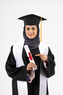 الاجتهاد والنجاح والتفوق، شابة سعودية تنظر الى الكاميرا بتعابير الفخر والسعادة بالوصول الى الحلم، مناسبة واحتفال جامعي، الاحتفال بإنهاء الدراسة الجامعية، بورتريه لخريجة عربية خليجية اماراتية محجبة ترتدي زي التخرج والقبعة تحمل بيدها الشهادة وتشير اليها، خلفية بيضاء