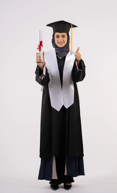 Expressions of happiness at achieving a dream, raising the thumb with gestures of satisfaction and admiration, the concept of success and excellence, a young Saudi woman celebrating the completion of university studies, a university occasion and celebration, a portrait of a veiled Arab Gulf Emirati graduate wearing a graduation gown and cap, holding a certificate in her hand, white background