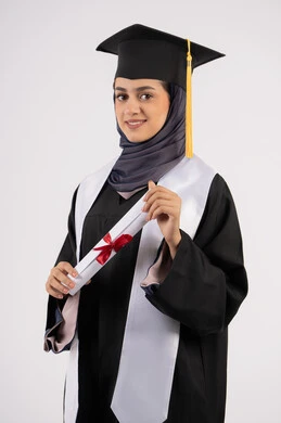 تعابير السعادة بالوصول الى الحلم، شابة سعودية تنظر الى الكاميرا بايماءات الفخر، مفهوم النجاح والتفوق، مناسبة واحتفال جامعي، الاحتفال بإنهاء الدراسة الجامعية، بورتريه لخريجة عربية خليجية اماراتية محجبة ترتدي زي التخرج والقبعة تحمل بيدها الشهادة، خلفية بيضاء