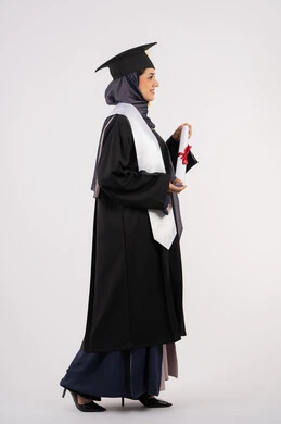 الاحتفال بإنهاء الدراسة الجامعية، مناسبة واحتفال جامعي، شابة سعودية تنظر الى مكان ما بايماءات الفخر، تعابير السعادة بالوصول الى الحلم، مفهوم النجاح والتفوق، بورتريه من الجانب لخريجة عربية خليجية اماراتية محجبة ترتدي زي التخرج والقبعة تحمل بيدها الشهادة، خلفية بيضاء