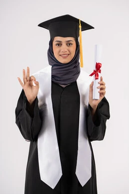 علامة الامتياز والتميز، تعابير السعادة بالوصول الى الحلم، شابة سعودية تنظر الى الكاميرا بايماءات الفخر، مفهوم النجاح والتفوق، الاحتفال بإنهاء الدراسة الجامعية، بورتريه لخريجة عربية خليجية اماراتية محجبة ترتدي زي التخرج والقبعة تحمل بيدها الشهادة، خلفية بيضاء