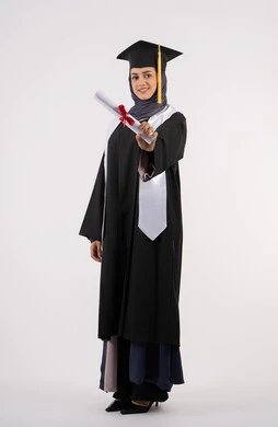 شابة سعودية تنظر الى الكاميرا بايماءات الفخر، تعابير السعادة بالوصول الى الحلم، مفهوم النجاح والتفوق، مناسبة واحتفال جامعي، الاحتفال بإنهاء الدراسة الجامعية، بورتريه لخريجة عربية خليجية اماراتية محجبة ترتدي زي التخرج والقبعة تحمل بيدها الشهادة، خلفية بيضاء