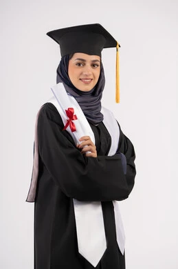Gestures of happiness for achieving a dream, university occasion and celebration, concept of success and excellence, young Saudi woman standing with crossed hands with expressions of pride, celebration of completing university studies, portrait of a veiled Arab Gulf Emirati graduate wearing graduation dress and cap holding a certificate, white background