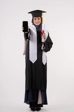 Online study applications, displaying a blank black screen on a mobile phone, portrait of a young Saudi Arabian Gulf Arab woman wearing a cap and graduation gown holding a diploma, a smiling Emirati graduate standing with an expression of pleasure and happiness, celebrating the end of the university stage, full body, white background