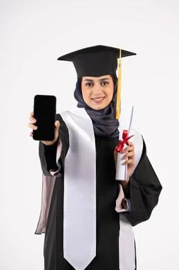 Blank black screen on mobile phone, portrait of a young Saudi Arabian Gulf Arab woman wearing a cap and graduation gown holding a diploma, smiling Emirati graduate standing with an expression of pleasure and happiness, online study applications, celebrating the end of the university stage, white background