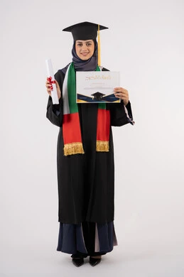 النجاح والتفوق والتخرج من الجامعة، إيماءات السعادة بالوصول الى الحلم، مناسبة واحتفال جامعي، الاحتفال بإنهاء الدراسة الجامعية، النظر الى الكاميرا بايماءات الفخر، بورتريه لخريجة عربية خليجية اماراتية محجبة ترتدي زي التخرج والقبعة تحمل بيدها الشهادة، خلفية بيضاء