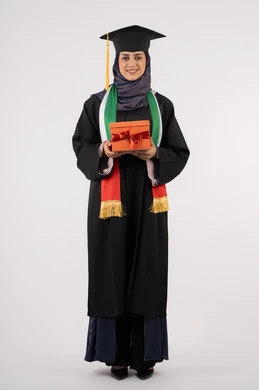 تعابير السعادة والسرور بالوصول لحلم النجاح، تقديم الهدايا في المناسبات، مفهوم الاجتهاد والتفوق، الاحتفال بإنهاء الدراسة الجامعية، مناسبة واحتفال جامعي، بورتريه لخريجة عربية خليجية اماراتية محجبة ترتدي زي التخرج والقبعة تمسك بيدها صندوق الهدية، خلفية بيضاء