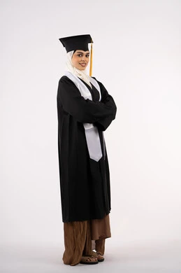 التقاط  صور شخصية بثياب التخرج، خريجة اماراتية تحتفل بإنهاء المرحلة الجامعية، بورتريه لشابة عربية خليجية سعودية مبتسمة ترتدي القبعة وعباءة التخرج تقف بأيدي متقاطعة وتنظر الى الكاميرا بتعابير السرور، مفهوم التفوق والنجاح والاجتهاد، صورة الجسم بالكامل، خلفية بيضاء