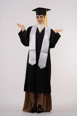 تعابير الأنوثة واللطافة، التقاط  صور شخصية بثياب التخرج، خريجة اماراتية تحتفل بإنهاء المرحلة الجامعية، بورتريه لشابة عربية خليجية سعودية مبتسمة ترتدي القبعة وعباءة التخرج تنظر الى الكاميرا بتعابير السرور، مفهوم التفوق والنجاح، صورة الجسم بالكامل، خلفية بيضاء