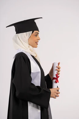 الوصول إلى الأحلام وتحقيقها، إيماءات الثقة بالنفس، التقاط  صور شخصية بثياب التخرج، خريجة سعودية تحتفل بإنهاء المرحلة الجامعية، بورتريه من الجانب لامرأة عربية خليجية اماراتية ترتدي القبعة وعباءة التخرج وتحمل الشهادة، خلفية بيضاء