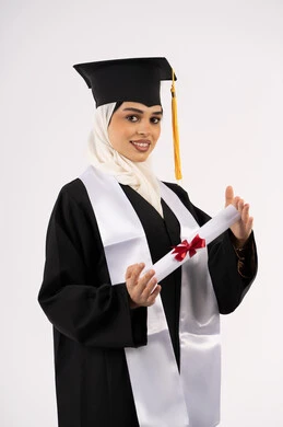 الحصول على شهادة التفوق، النظر إلى الكاميرا بإيماءات السعادة والفرح، الاحتفال بالوصول إلى الأحلام، التقاط  صور شخصية بثياب التخرج، خريجة سعودية تحتفل بإنهاء المرحلة الجامعية، بورتريه لامرأة عربية خليجية اماراتية ترتدي القبعة وعباءة التخرج، خلفية بيضاء