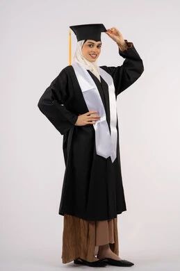 الفرح بتحقيق النجاح, أهمية الدراسة الجامعية، مفهوم الاجتهاد والتفوق، ايماءات البهجة والسعادة والفخر بالوصول لحلم التخرج، بورتريه لخريجة عربية سعودية خليجية محجبة مبتسمة ترتدي العباءة وقبعة التخرج، شابة إماراتية تحتفل بإنهاء دراستها، صورة لكامل الجسم، خلفية بيضاء