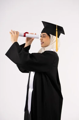 Pride and joy of achieving the graduation dream, looking forward to the future after graduation, side portrait of a veiled Saudi Arabian Gulf graduate wearing graduation gown and looking through her certificate of excellence, a young Emirati woman celebrating the completion of her studies, white background