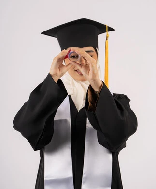 مناسبة واحتفال جامعي، التطلع إلى الأهداف والطموحات المستقبلية، الفخر والفرح بالوصول لحلم التخرج, بورتريه لخريجة عربية سعودية خليجية محجبة مبتسمة ترتدي ثياب التخرج وتنظر إلى الكاميرا من خلال شهادة التفوق، شابة إماراتية تحتفل بإنهاء دراستها، خلفية بيضاء