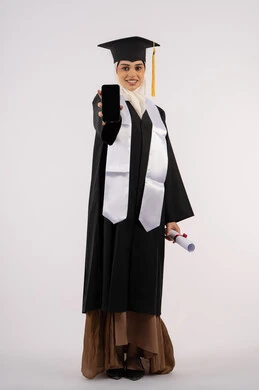 عرض شاشة سوداء فارغة على الهاتف المحمول، تطبيقات التعليم والدراسة اونلاين، بورتريه لشابة عربية خليجية سعودية ترتدي القبعة وزي التخرج تمسك بيدها الشهادة، خريجة اماراتية مبتسمة تقف بتعابير السرور، الاحتفال بانتهاء المرحلة الجامعية، الجسم بالطول الكامل، خلفية بيضاء
