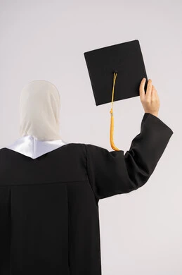 التعليم في الامارات العربية المتحدة، الشعور بالفخر والفرح بالوصول لحلم التخرج, بورتريه من الخلف لخريجة عربية سعودية خليجية محجبة ترتدي عباءة وترفع قبعة التخرج، شابة إماراتية تحتفل بإنهاء دراستها الجامعية، خلفية بيضاء