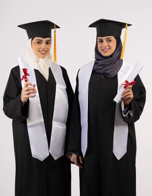 الاحتفال مع الأصدقاء بالتخرج من الجامعة، مفهوم الاجتهاد والتفوق، النظر إلى الكاميرا بإيماءات السعادة والفخر، بورتريه لخريجتين جامعيتين عربيتين خليجيتين اماراتيتين ترتديان ملابس التخرج وتمسكان وثيقة التفوق، خلفية بيضاء