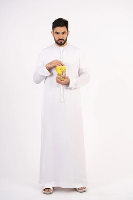 إيماءات وجه ويدين تدل على الغضب ، قضاء أوقات ممتعة ، مفهوم التسليه والترفيه، رجل عربي خليجي اماراتي يرتدي الزى التقليدي يحمل بيده علبة الفشار ويقوم بمشاهده الافلام ، مشاهدة فيلم سينمائي