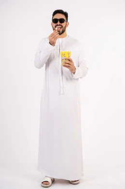 الاستمتاع بتناول البوب كورن ،مفهوم التسليه والترفيه،  قضاء أوقات ممتعة ومسلية، بورتريه لرجل عربي خليجي اماراتي يرتدي الزى التقليدي يحمل بيده علبة الفشار ويقوم بمشاهده الافلام ، مشاهدة فيلم سينمائي ، خلفيه بيضاء