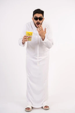 إيماءات وجه ويدين تدل على الصدمه والذهول ،  النظر بتعابير المفاجأه ،مفهوم التسليه والترفيه، قضاء أوقات ممتعة ومسلية، بورتريه لرجل عربي خليجي اماراتي يرتدي الزى التقليدي يحمل بيده علبة الفشار ويقوم بمشاهده الافلام ، مشاهدة فيلم سينمائي ، خلفيه بيضاء