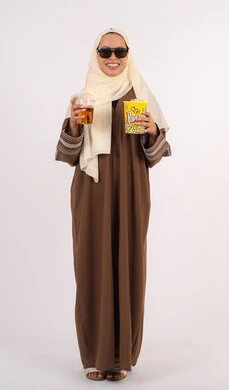 الاستمتاع باكل البوب كورن وشرب المشروبات البارده ، قضاء أوقات ممتعة ، الاستمتاع بمشاهدة الأفلام داخل السينما، مفهوم التسلية والترفيه ، متابعة الفيلم المفضل،بورتريه لامرأة عربية خليجية اماراتيه محجبة ترتدي عباءه وتحمل علبه فوشار ، خلفية بيضاء