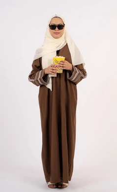 اكل البوب كورن ، الاستمتاع بمشاهدة الأفلام داخل السينما، التسلية والترفيه بقضاء أوقات ممتعة، متابعة الفيلم المفضل،بورتريه لامرأة عربية خليجية اماراتيه محجبة ترتدي عباءه وتحمل علبه فوشار ، خلفية بيضاء