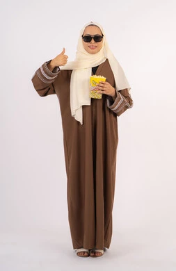 تعابير الموافقه والرضي ، الاستمتاع بمشاهدة الأفلام داخل السينما، اكل البوب كورن ، التسلية والترفيه بقضاء أوقات ممتعة، متابعة الفيلم المفضل،بورتريه لامرأة عربية خليجية اماراتيه محجبة ترتدي عباءه وتحمل علبه فوشار ، خلفية بيضاء