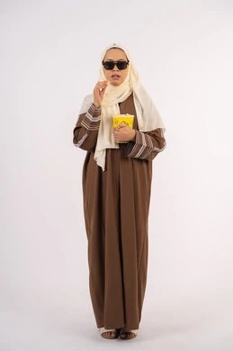 الاستمتاع بمشاهدة الأفلام داخل السينما، بورتريه لامرأة عربية خليجية اماراتيه محجبة ترتدي عباءه ، وتأكل حبات الفوشار، التسلية والترفيه بقضاء أوقات ممتعة، متابعة الفيلم المفضل، خلفية بيضاء