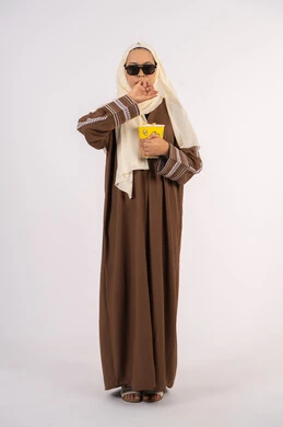 تعابير الارهاق والنعاس ، الاستمتاع بمشاهدة الأفلام داخل السينما، بورتريه لامرأة عربية خليجية اماراتيه محجبة ترتدي عباءه وتحمل كيس فوشار ، التسلية والترفيه بقضاء أوقات ممتعة، متابعة الفيلم المفضل، خلفية بيضاء