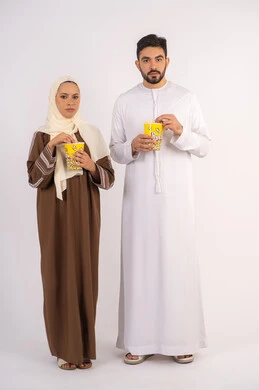 بورتريه لزوجيين عربيين خليجيين اماراتيين مبتسميين ينظران الى الكاميرا، تعابير الاندماج والتفاعل،الاستمتاع بالأنشطة العائلية الترفيهيه، تناول الفوشار اثناء متابعة الأفلام والمسلسلات، قضاء وقت ممتع في السينما،خلفية بيضاء