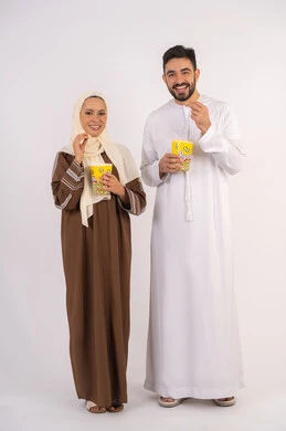 اجواء عائليه سعيده ،الاستمتاع بالأنشطة العائلية الترفيهيه، تناول الفوشار اثناء متابعة الأفلام والمسلسلات، قضاء وقت ممتع في السينما، بورتريه لزوجيين عربيين خليجيين اماراتيين مبتسميين ينظران الى الكاميرا بتعابير السرور والسعادة، خلفية بيضاء