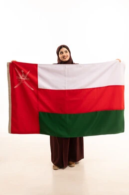 Pride and honor in the symbols and flag of Oman, celebrating the anniversary of Omani National Day, participating in national holidays and events, a portrait of a smiling Omani Gulf Arab woman wearing a hijab and an abaya holding the flag of the Sultanate of Oman, the concept of love for the homeland and belonging to it, full-body, white background. Pride and honor in the symbols and flag of Oman, celebrating the anniversary of Omani National Day, participating in national holidays and events, a portrait of a smiling Omani Gulf Arab woman wearing a hijab and an abaya holding the flag of the Sultanate of Oman, the concept of love for the homeland and belonging to it, full-body, white background.