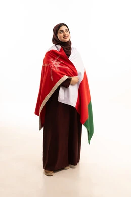 Celebrating the anniversary of Oman's National Day, participating in national holidays and events, pride and honor in the symbols and flag of Oman, a portrait of a smiling Omani Gulf Arab woman wearing a hijab and an abaya holding the flag of the Sultanate of Oman, the concept of love for the homeland and belonging to it, full-body, white background.