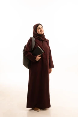 التعليم والتعلم في الكليات السعودية،  النظر الى شيء ما ، الأكاديميات التعليمية في دول الخليج, بورتريه لطالبة جامعية عربية خليجية سعودية محجبة ترتدي العباءة وحقيبة الظهر تمسك بيديها الكتب الجامعية , صورة الجسم بالطول الكامل, خلفية بيضاء